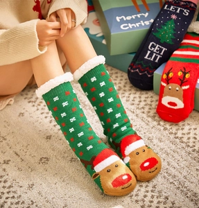 Detail of green knitted Christmas reindeer socks with white faux fur lining worn by a model