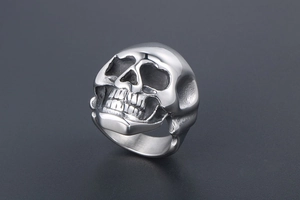 Macro shot of silver stainless steel skull ring with detailed punk style carvings