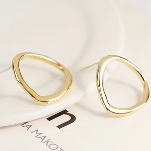 Macro shot of gold irregular baroque pearl earrings displayed on a white ceramic plate