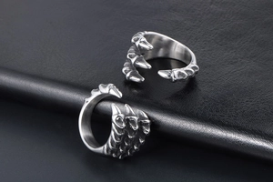 Detailed view of vintage silver dragon claw rings with textured metal on dark leather surface