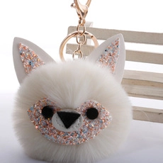 Close-up of a white plush fox keychain charm with sparkling glitter and gold-tone clasp
