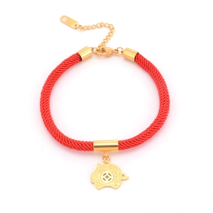 Detail of red woven bracelet featuring a gold pig charm with lucky coin cutout and lobster clasp