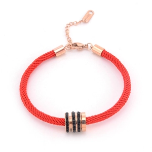 Detail of red woven cord bracelet featuring a rose gold cylinder charm with black crystals