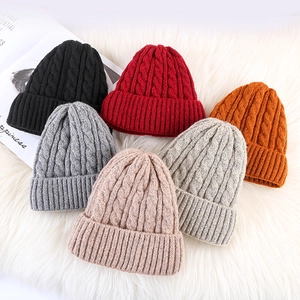 Thick mohair knit beanie hats in multiple colors on a soft white plush background