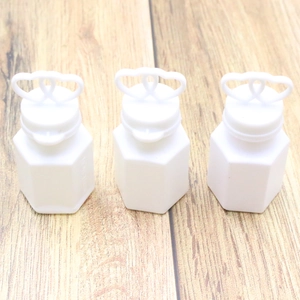 Three white plastic bubble wand bottles with heart shaped caps on a wooden background