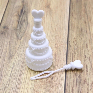 Close-up of white cake-shaped wedding bubble bottle with heart wand on wooden background