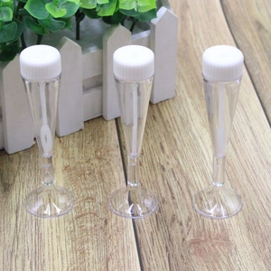 Three transparent bubble tubes with white caps on a wooden surface for wedding decor