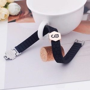 Black silicone sports bracelet with rose gold metal accents shown on a white ceramic mug