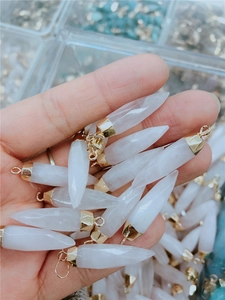 Macro detail of hexagonal white crystal pendants with golden metal caps and faceted finish