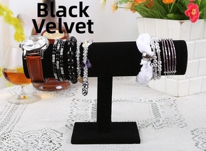 Detail of black velvet T-bar display stand holding watches and bracelets on a lace table