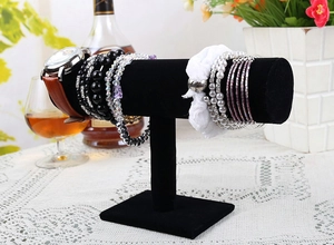 Close-up of black velvet T-bar jewelry stand displaying pearl bracelets and watches