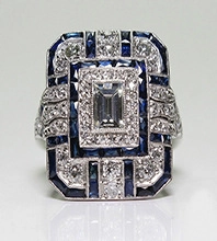Macro shot of Art Deco ring with emerald-cut center stone and blue sapphire border