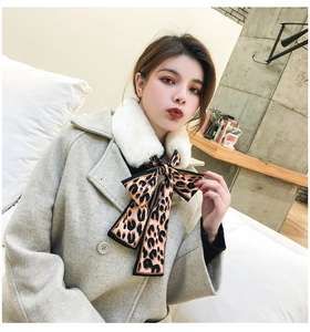 Detail view of white faux rabbit fur scarf with leopard print ribbon on a beige coat