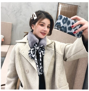 Detail of faux rabbit fur scarf with leopard print bow on a beige coat outfit