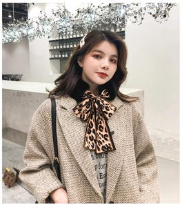 Detail of leopard print ribbon scarf with black faux fur collar on tweed coat