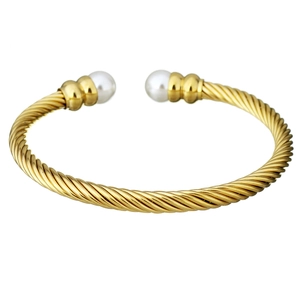 Detail of gold twisted cable bangle featuring two lustrous white pearls on a white background