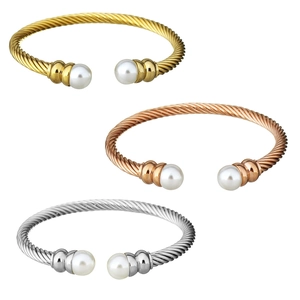Detailed view of twisted open bangles in gold, rose gold and silver with white pearls