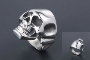Macro detail of silver skull ring showing intricate carving and polished steel finish
