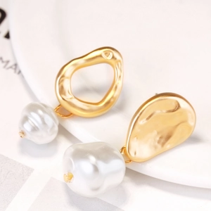 Detail of asymmetrical baroque pearl earrings with irregular gold-tone metal elements