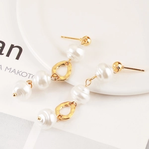 Detail of baroque pearl drop earrings with hammered gold finish and tiered structure