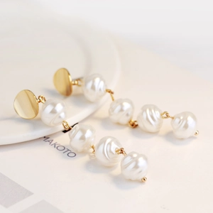Detail of baroque pearl drop earrings with elegant spiral textures and golden bases