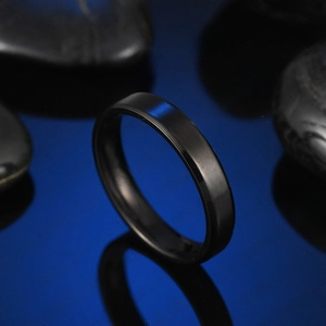 Macro shot of 4mm black beveled stainless steel ring on a dark reflective surface