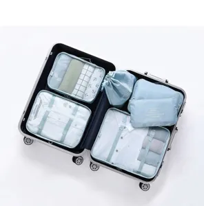 Detalle de seis organizadores de viaje azul claro dentro de una maleta plateada