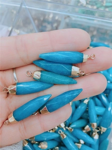 Detail showing conical turquoise natural stone pendants with golden metal caps and loops