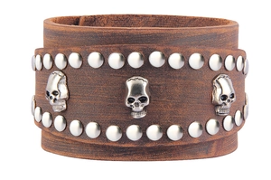 Detail view of brown leather punk bracelet featuring silver skull badges and metal rivets