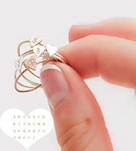 Close-up of personalized rose gold and silver heart rings with custom A-Z letter engraving