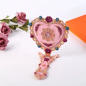 Detail eines rosa Vintage-Herzspiegels mit goldenem Filigran und Rosenakzenten