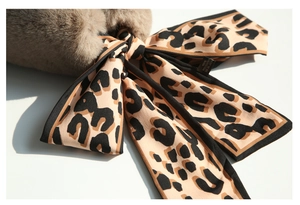 Detail of leopard print silk ribbon tied on brown faux rabbit fur winter neck warmer