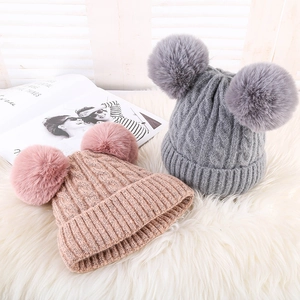 Detail shot of cute knit beanies in pink and grey with double faux fur pom poms