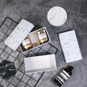 Detailed top view of a white marble gift box and golden soy wax scented candle set