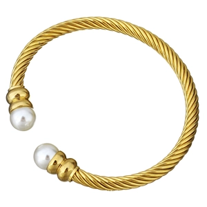 Detailed macro view of the twisted metal texture and white pearls on this golden cuff