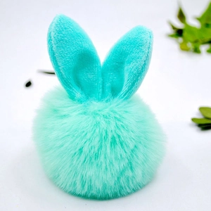 Detailed close-up of teal faux fur pom pom keychain with cute bunny ears on white background