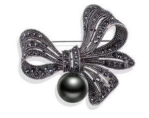 Retro gun black bow brooch with dark rhinestones and a hanging black pearl on white background