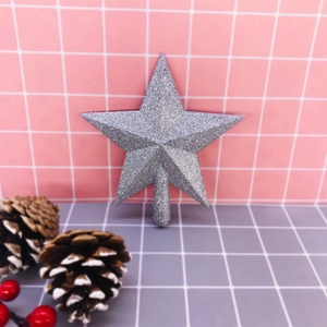Detail of silver glitter star tree topper with pine cones and red berries decoration
