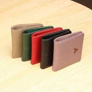 Short leather wallets in five colors with a golden deer ornament on a wooden surface
