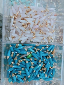 Bulk faceted teardrop crystal pendants in pink and blue with gold caps in a container