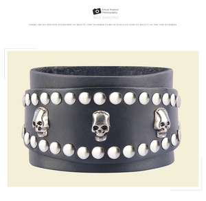 Detailed macro of black leather punk bracelet with silver skull charms and metal rivets