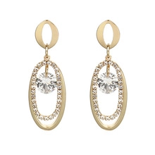 Détail de boucles d'oreilles ovales dorées avec perles et accents de micro-pavé