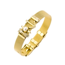 Detail showing golden mesh strap bracelet with white pearls and geometric charms