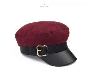 Detail of burgundy wool newsboy cap with black leather brim and gold buckle
