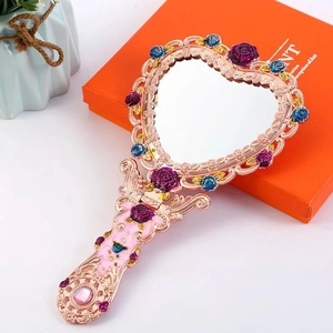 Nahaufnahme eines Vintage-Handspiegels in Herzform mit roségoldenem Relief und Emaille