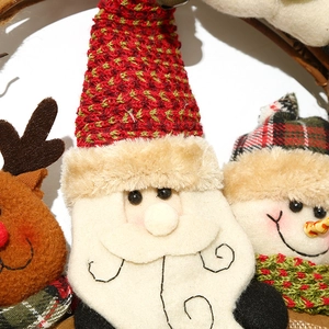 Detalle de corona navideña mostrando texturas de Papá Noel, reno y muñeco de peluche