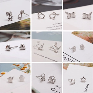 Close-up of minimalist silver stud earrings in various shapes like heart and clover