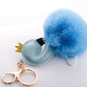 Detail of blue swan plush ball keychain with golden crown and leather wing detail