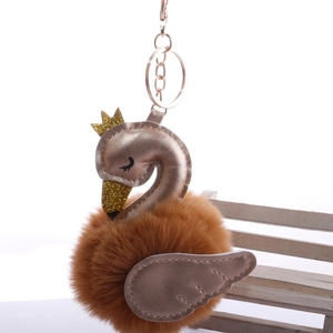 Detailed view of champagne gold swan head with crown on soft camel fur pompom keychain