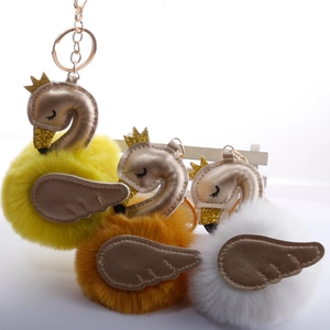 Detail of plush swan pompom keychains in yellow, orange, and white with gold crowns